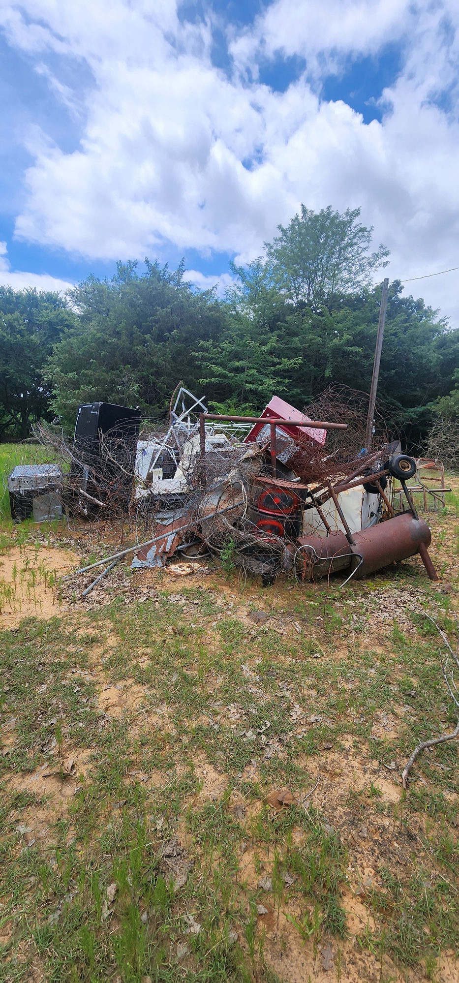 Property piled with scrap metal, wire, and debris before Cowboy Site Services cleared it